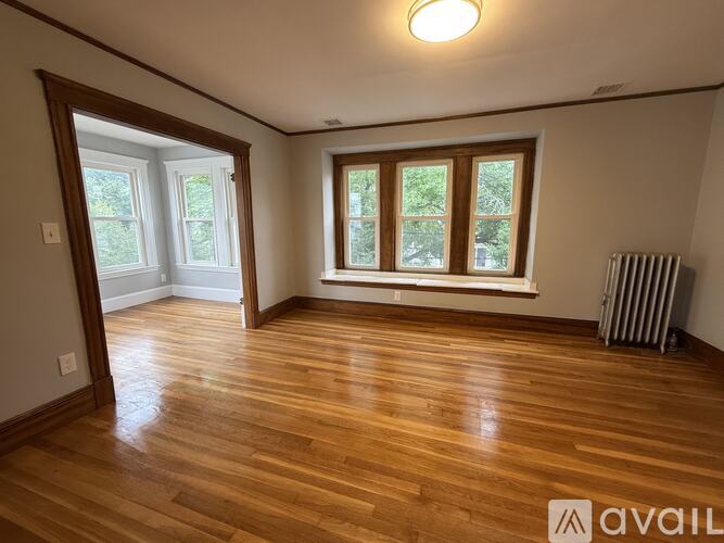 A room with wooden floors and a window with a view of trees.
