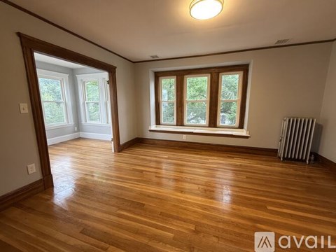 A room with wooden floors and a window with a view of trees.