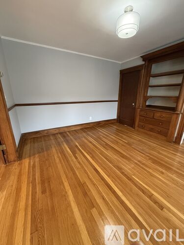 A room with wooden flooring and a wooden wardrobe.