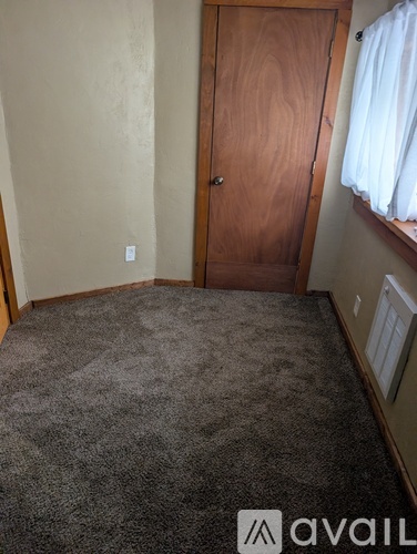 A room with a carpeted floor and a wooden door.