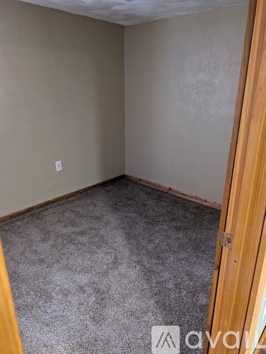 A room with a carpeted floor and a wooden door.