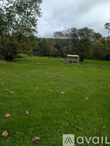 A grassy field with a small shelter and trees in the background.