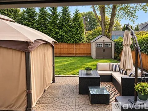 A backyard with a patio, a hot tub, and a small shed.