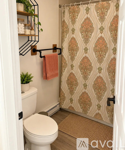 A bathroom with a toilet, a shower curtain, and a towel rack.