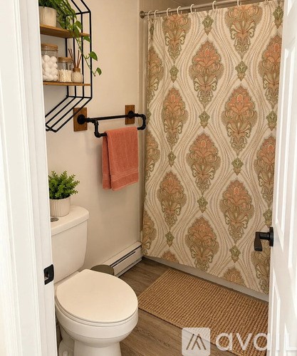A bathroom with a toilet, a shower curtain, and a towel rack.