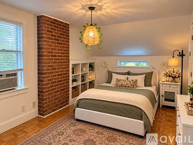 A bedroom with a brick column and a bed with a white comforter.