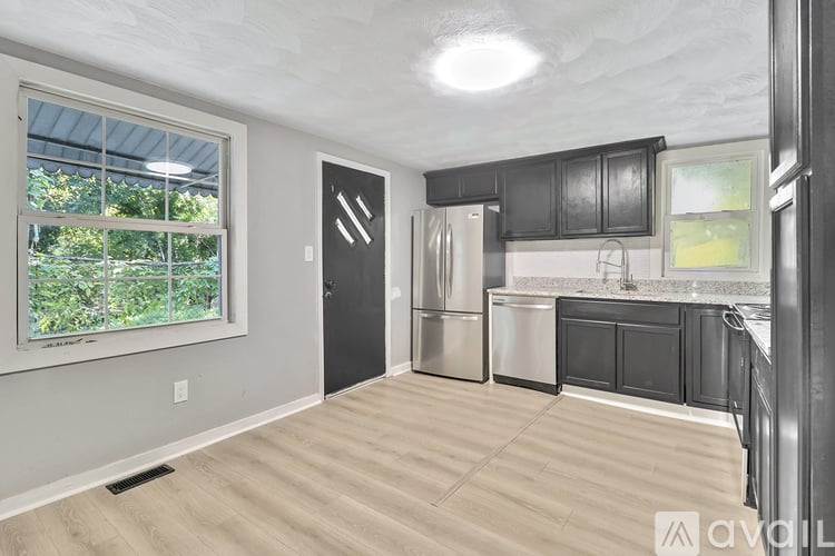 A kitchen with black cabinets and a refrigerator.
