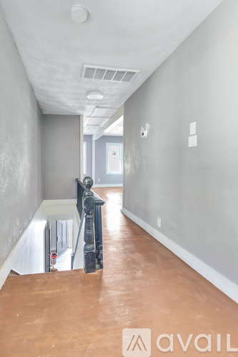 A hallway with a wooden floor and a staircase.
