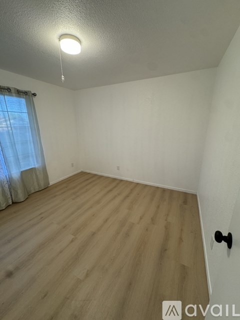 A room with wooden flooring and a window with curtains.
