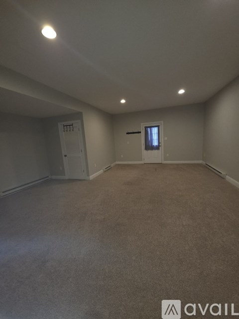 A spacious room with carpeted floor and two doors.