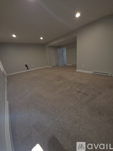 A spacious room with carpeted floor and white walls.