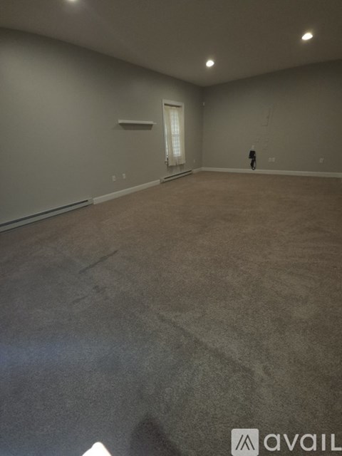 A large empty room with carpeted floor and white walls.