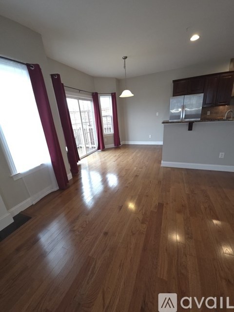 A room with wooden floors and a kitchen area with a sink and cabinets.