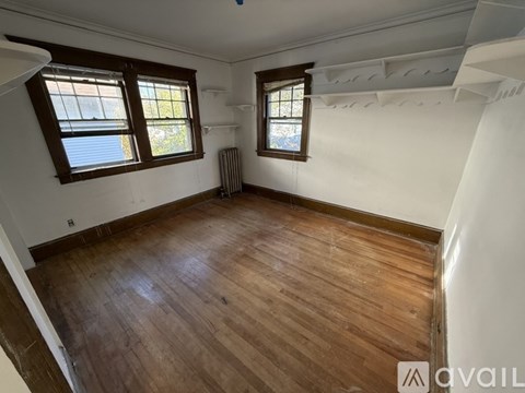 A room with wooden floors and two windows.