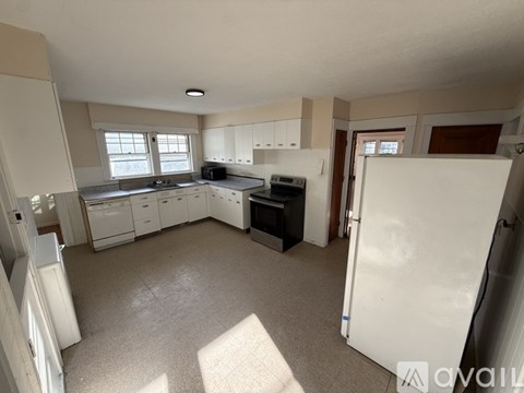 A kitchen with white appliances and cabinets is available for rent.
