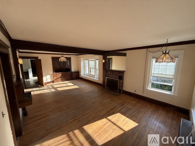 A large empty room with wooden floors and a fireplace.