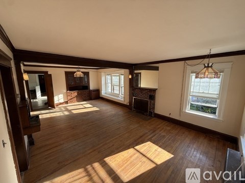 A large empty room with wooden floors and a fireplace.