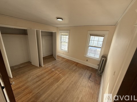 A room with wooden floors and two windows.