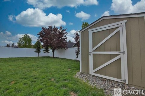 A shed with a white door is situated in a grassy area.