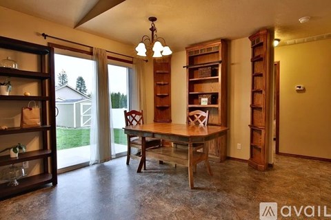 A room with a table, chairs, and a cabinet with shelves.