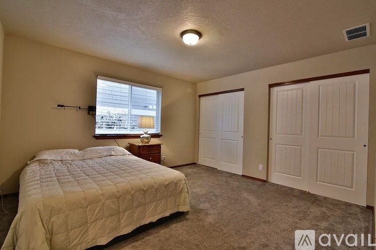A bedroom with a bed, dresser, and window.