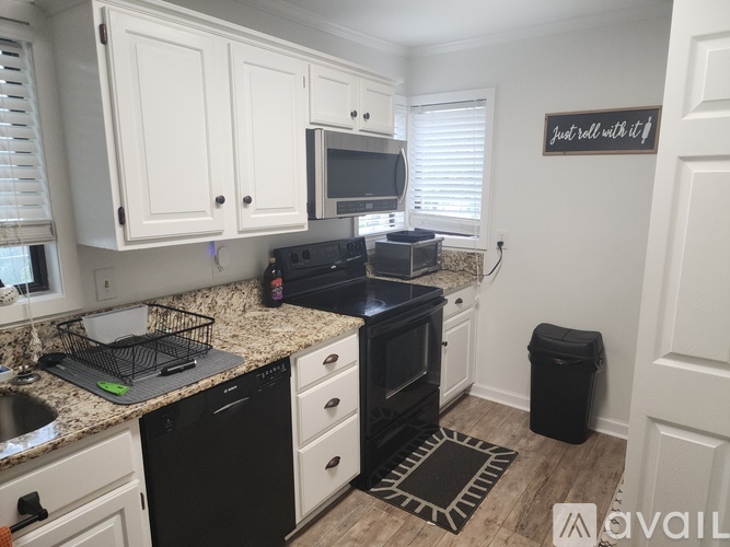 A kitchen with black appliances and white cabinets.