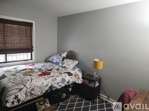 A bedroom with a bed, a lamp, and a window with blinds.