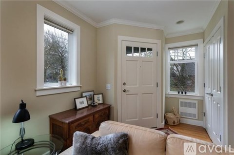 A living room with a couch, a table with a lamp, and a window.
