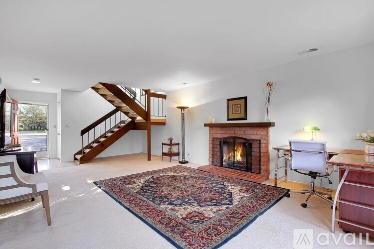A living room with a fireplace and a rug on the floor.