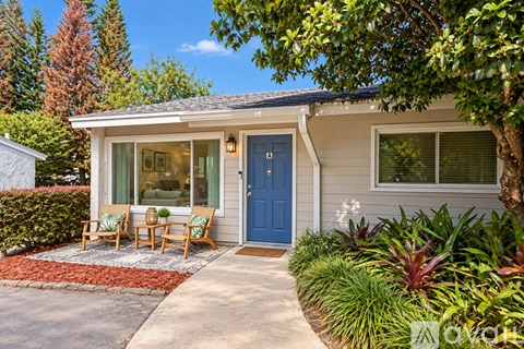 A small house with a blue door and a red brick walkway.