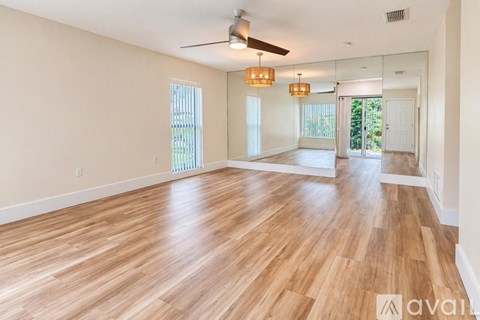 A spacious room with wooden flooring and a ceiling fan.