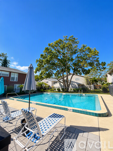 A pool with a tree in the background and chairs around it.
