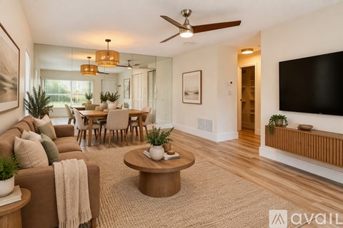 A living room with a brown couch, a coffee table, and a flat screen TV mounted on the wall.