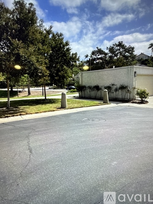 A parking lot with a building and trees in the background.
