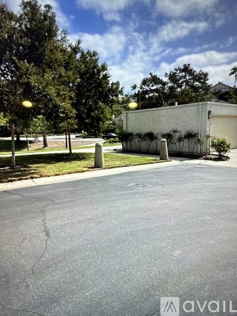 A parking lot with a building and trees in the background.