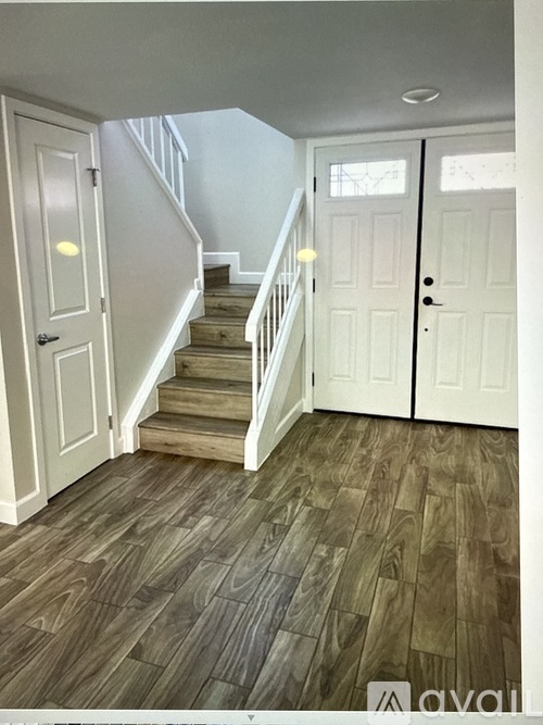 A hallway with a staircase and two doors.