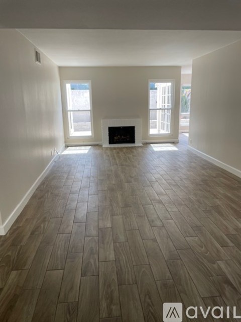 A spacious room with a fireplace and wood flooring.