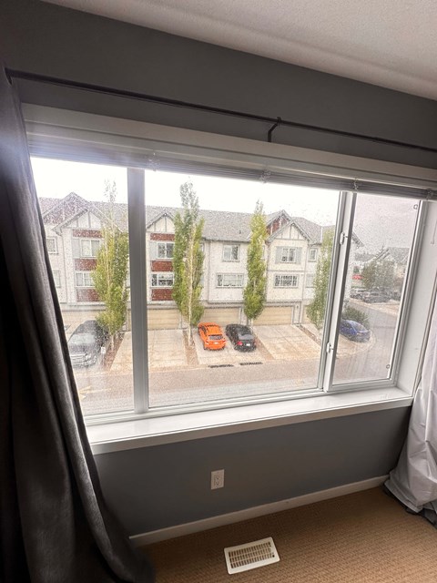 A window with a view of a parking lot and buildings outside.