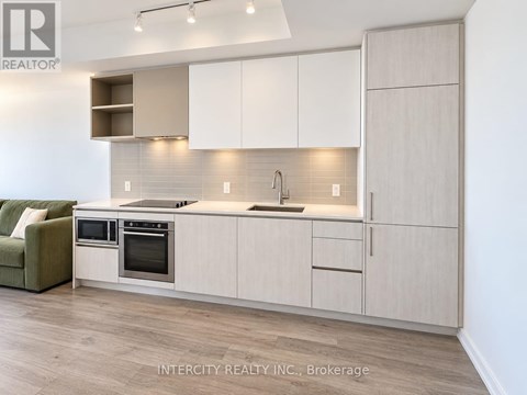 A modern kitchen with white cabinets and a green sofa.