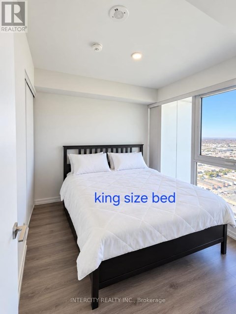 A bedroom with a king size bed and a view of the city.