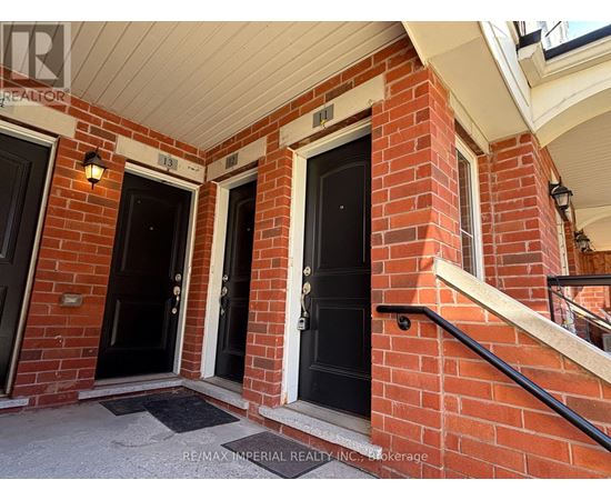 A red brick house with two black doors and a small porch.