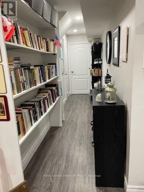 A hallway with a black cabinet and a bookshelf with books and flags.