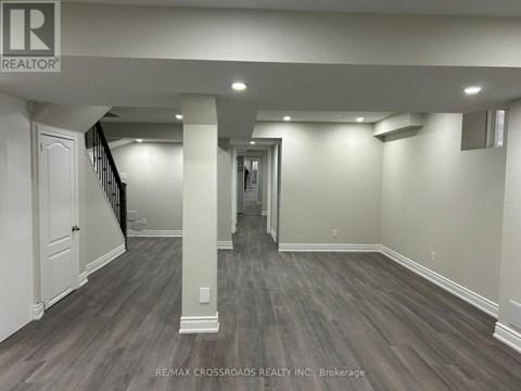 A spacious room with wooden flooring and white walls.