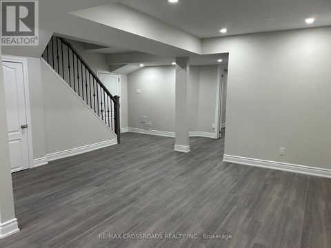 A spacious room with wooden flooring and a staircase.