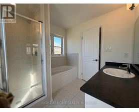 A bathroom with a glass shower door and a black countertop.