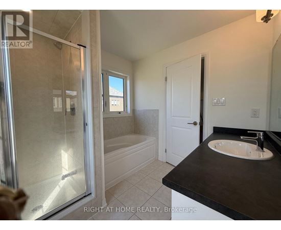 A bathroom with a glass shower door and a black countertop.