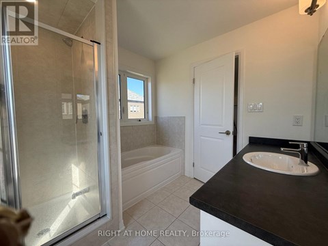 A bathroom with a glass shower door and a black countertop.