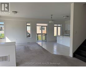 A spacious, empty room with a staircase leading to the upper floor.