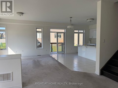 A spacious, empty room with a staircase leading to the upper floor.