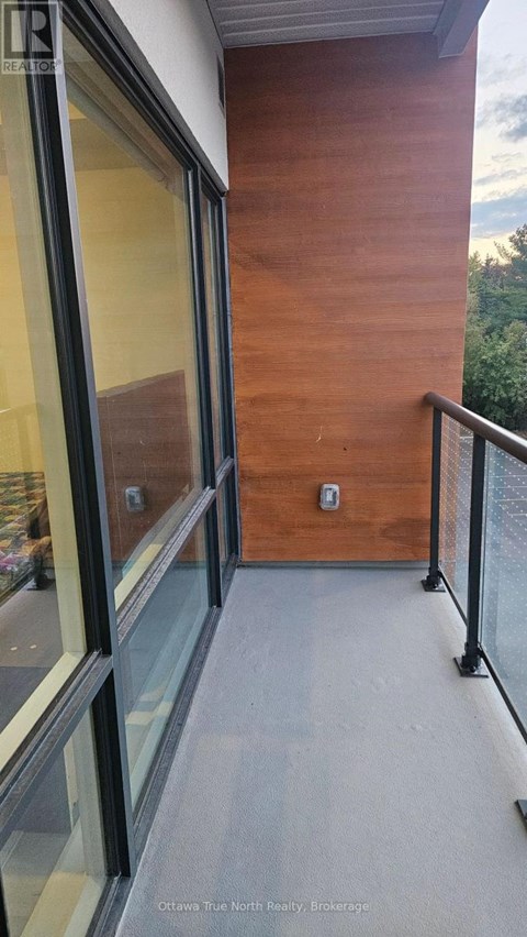 A balcony with a glass railing and a wooden wall.